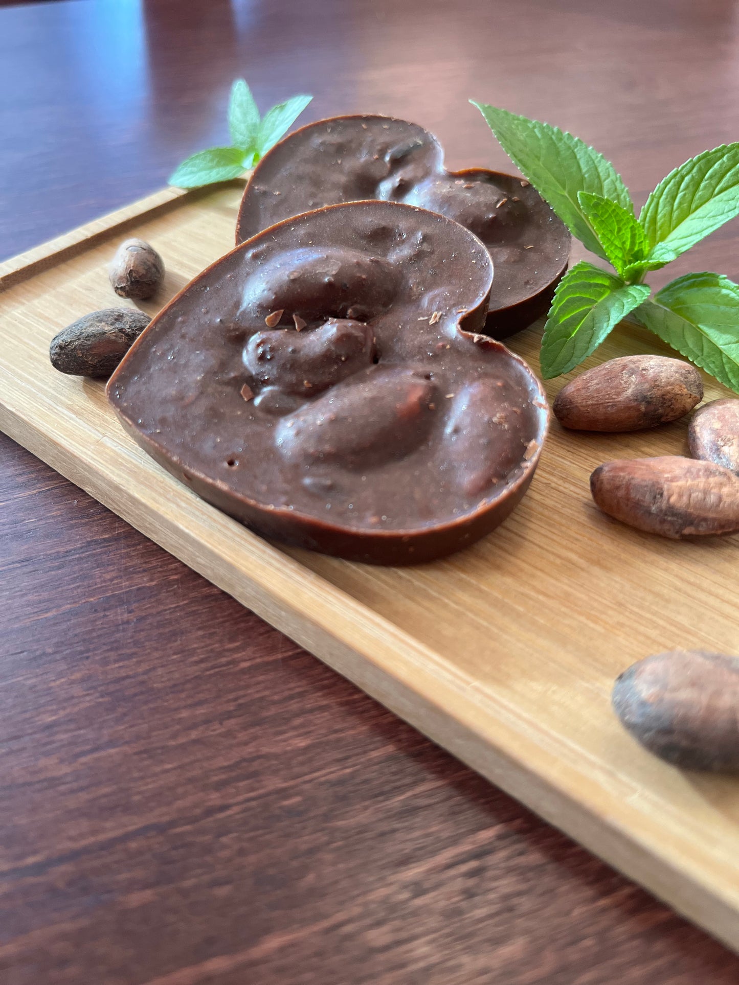 Side view of whole cacao Peppermint treats with fresh peppermint leaves and cacao beans